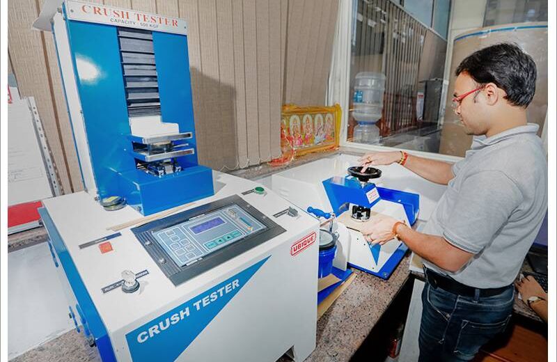 Technician testing box strength on a crush tester