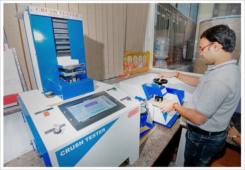 Technician testing box strength on a crush tester